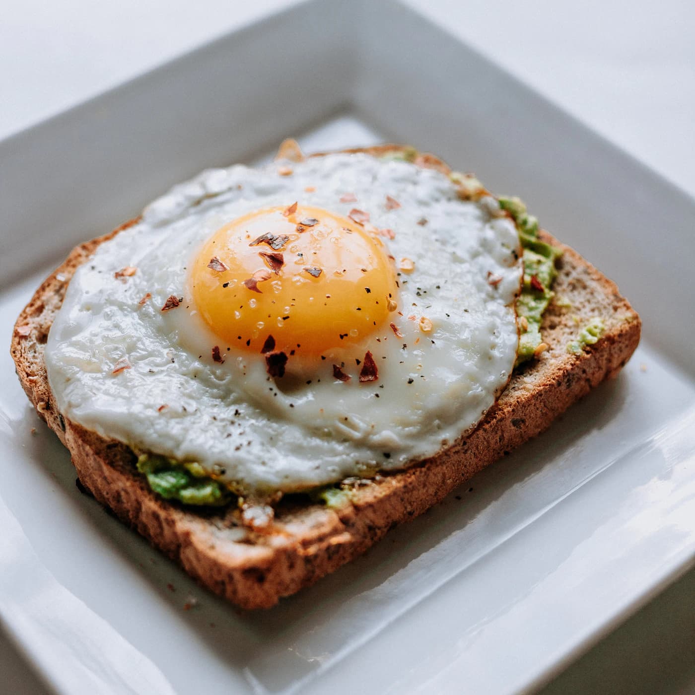 Fried egg on whole-grain toast with smashed avocado.
