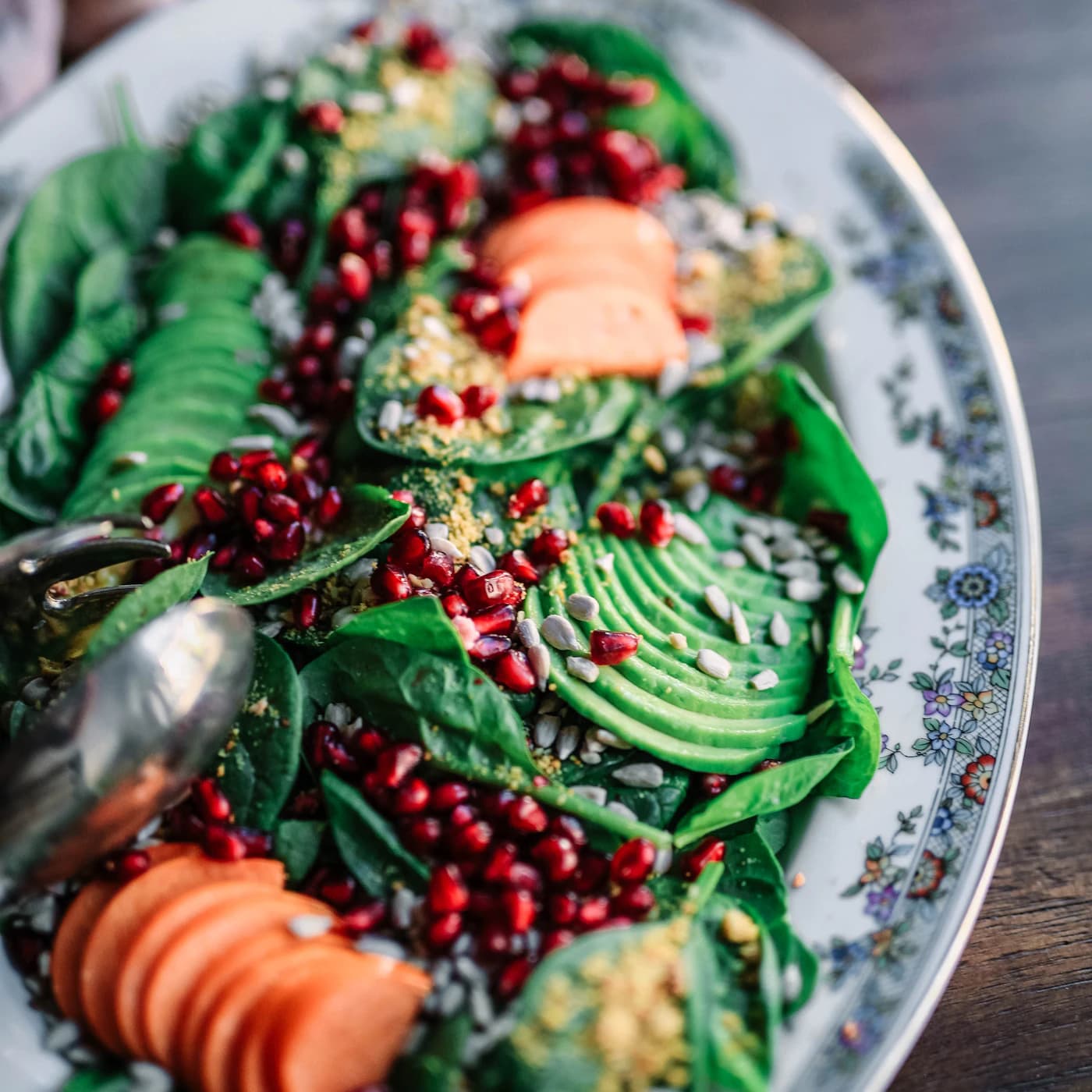 Platter of kale, avocado, pomegranate seeds and sliced carrots.