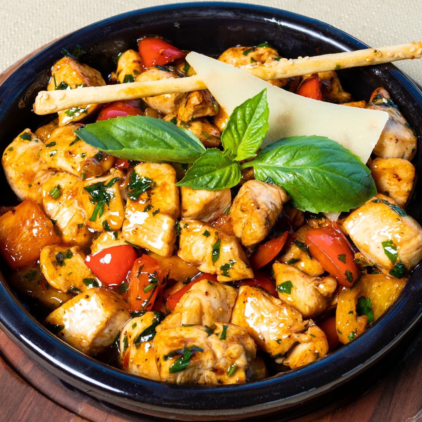 Skillet of chicken pieces with tomatoes, basil and parmesan.