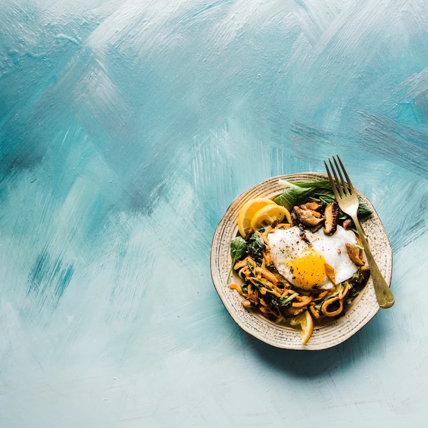 Bowl of sesame noodles with a soft egg and vegetables.