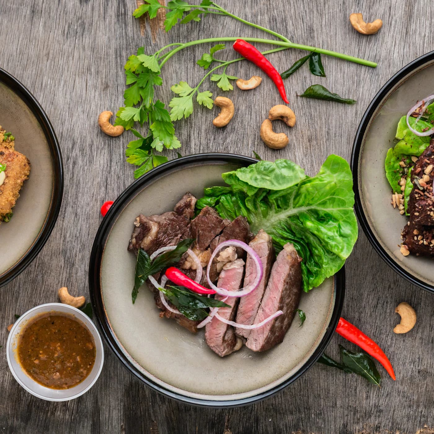 Sliced medium-rare sirloin with leafy greens and red onion on a plate.