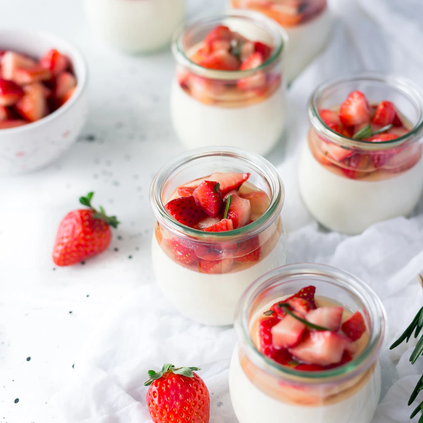 Small jars of yogurt topped with fresh strawberries.
