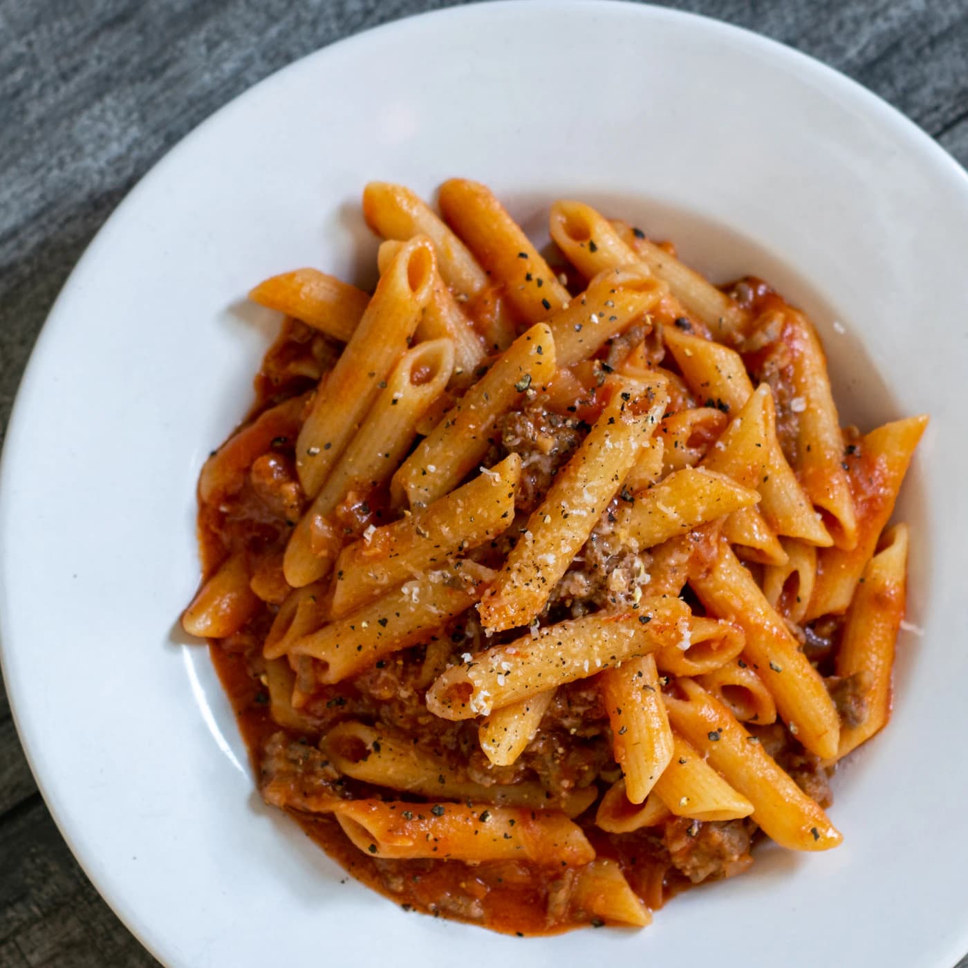 Plate of penne in a tomato meat sauce with parmesan.
