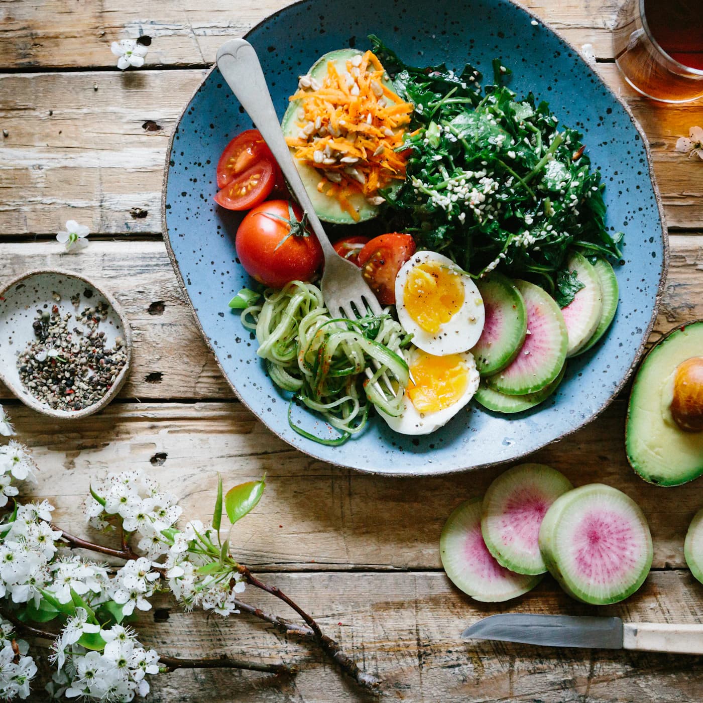 Plate of zucchini noodles, soft-boiled eggs, spinach, tomato and avocado.
